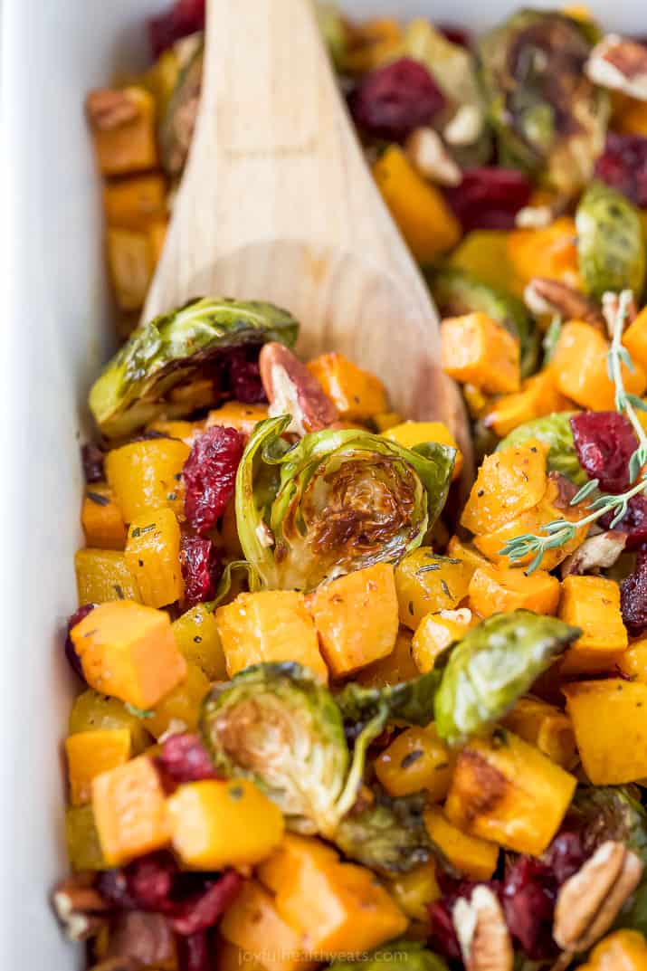 a wooden spoon scooping maple dijon roasted butternut squash brussel sprout salad