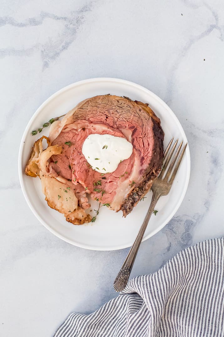 perfect garlic herb prime rib roast on a plate with creamy horseradish