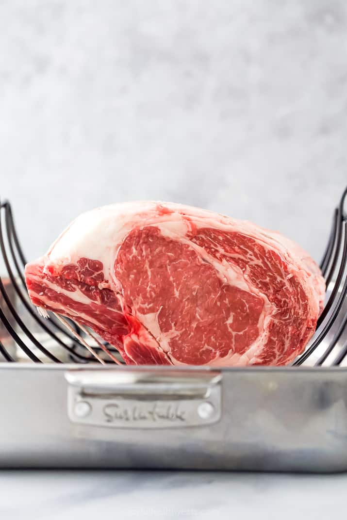 Raw prime rib roast in roasting pan.