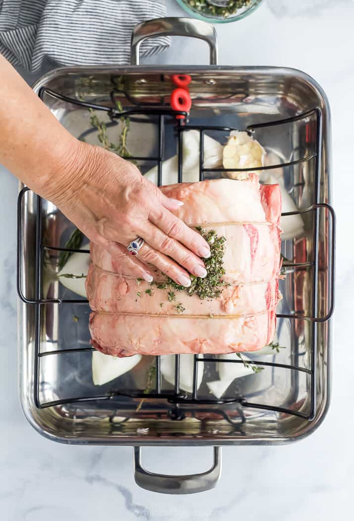 Rubbing herb paste onto prime rib.