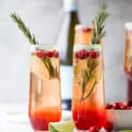 two side by side glasses filled with easy cranberry mimosa recipe with garnish
