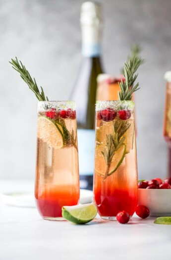 two side by side glasses filled with easy cranberry mimosa recipe with garnish