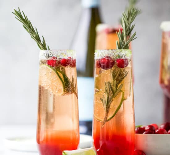 two side by side glasses filled with easy cranberry mimosa recipe with garnish