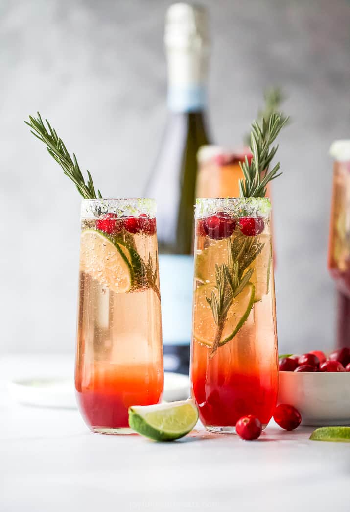 two side by side glasses filled with easy cranberry mimosa recipe with garnish