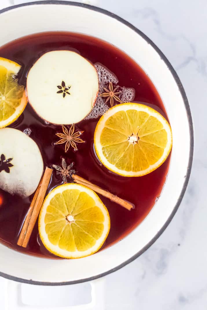 overhead photo of festive spiked cranberry mulled apple cider in a dutch oven