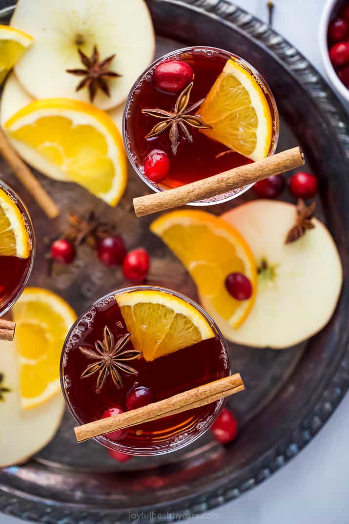 overhead photo of festive spiked cranberry mulled apple cider garnished with cinnamon and cranberries