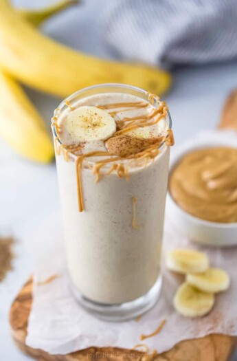 A glass of peanut butter banana smoothie with more peanut butter on top.