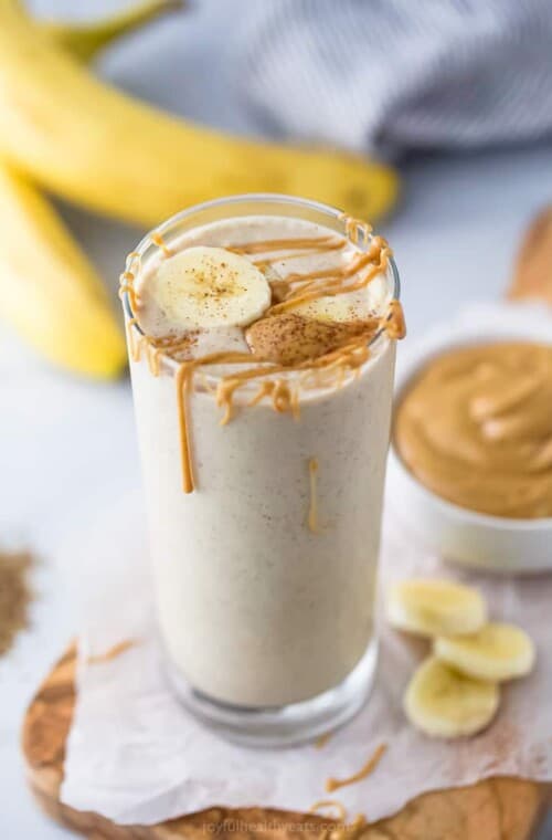 A glass of peanut butter banana smoothie with more peanut butter on top.