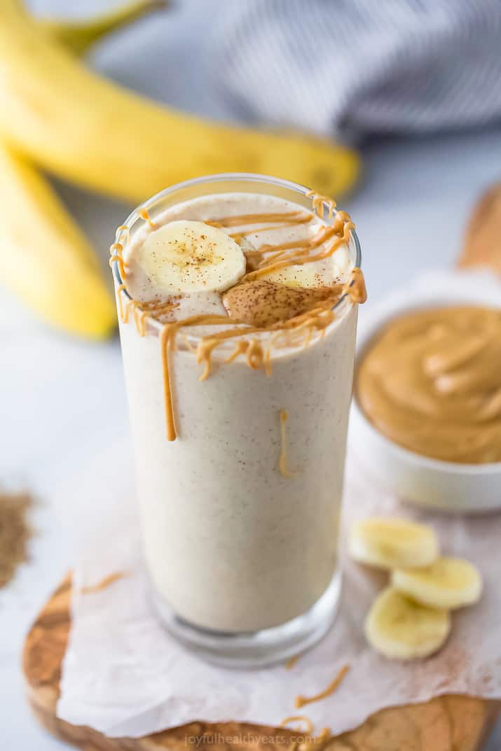 A glass of peanut butter banana smoothie with more peanut butter on top. 