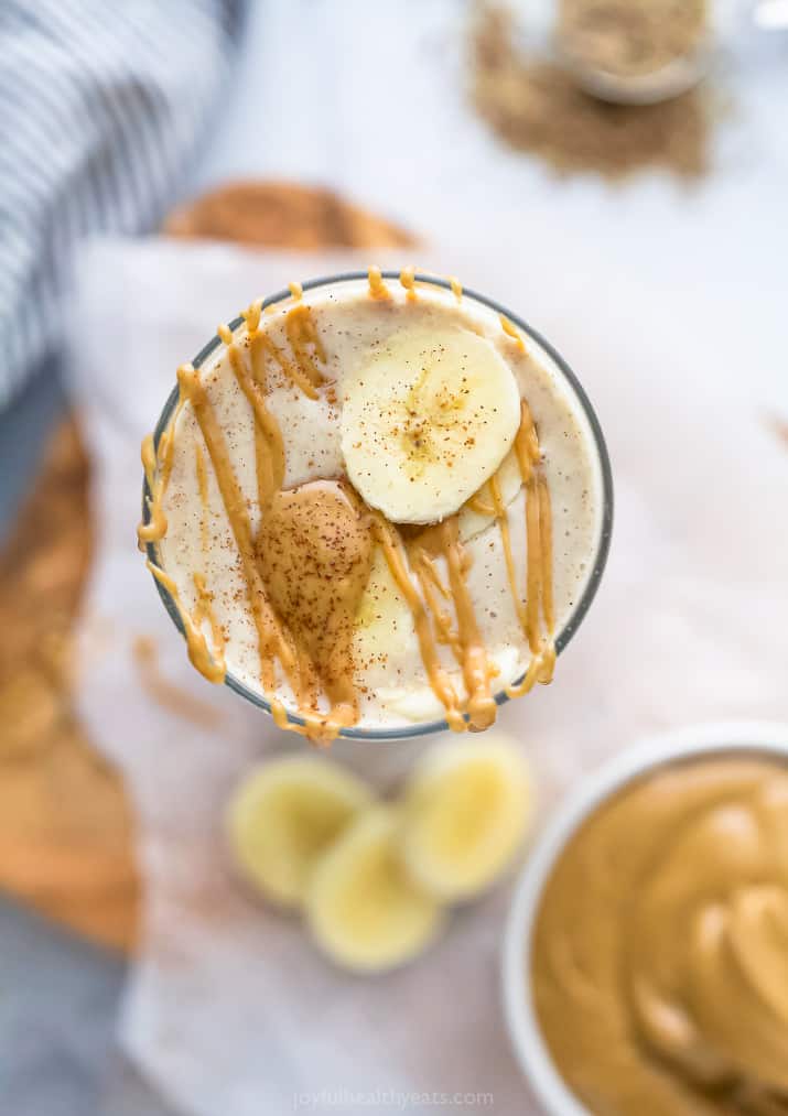 overhead photo of creamy peanut butter banana smoothie with peanut butter drizzle and banana on top