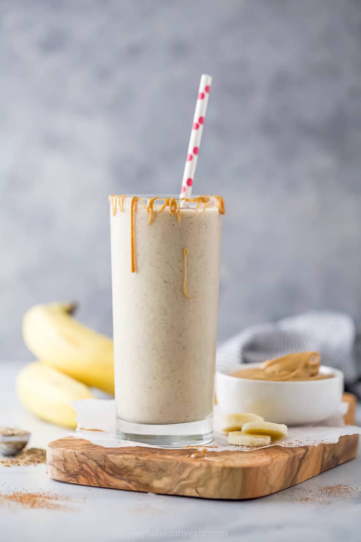 Gl، of peanut ،er banana smoothie with a straw. 