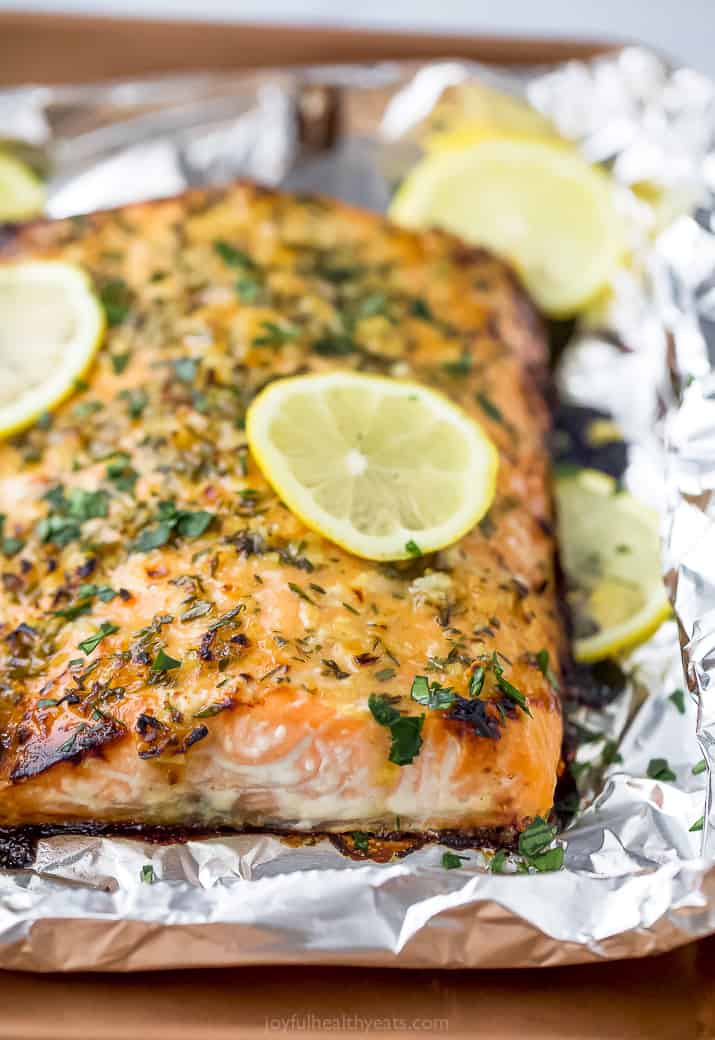 Close up photo of baked honey garlic salmon in foil topped with lemon.