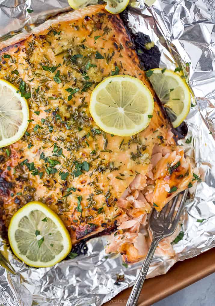 Baked honey garlic salmon in foil with lemons on top.