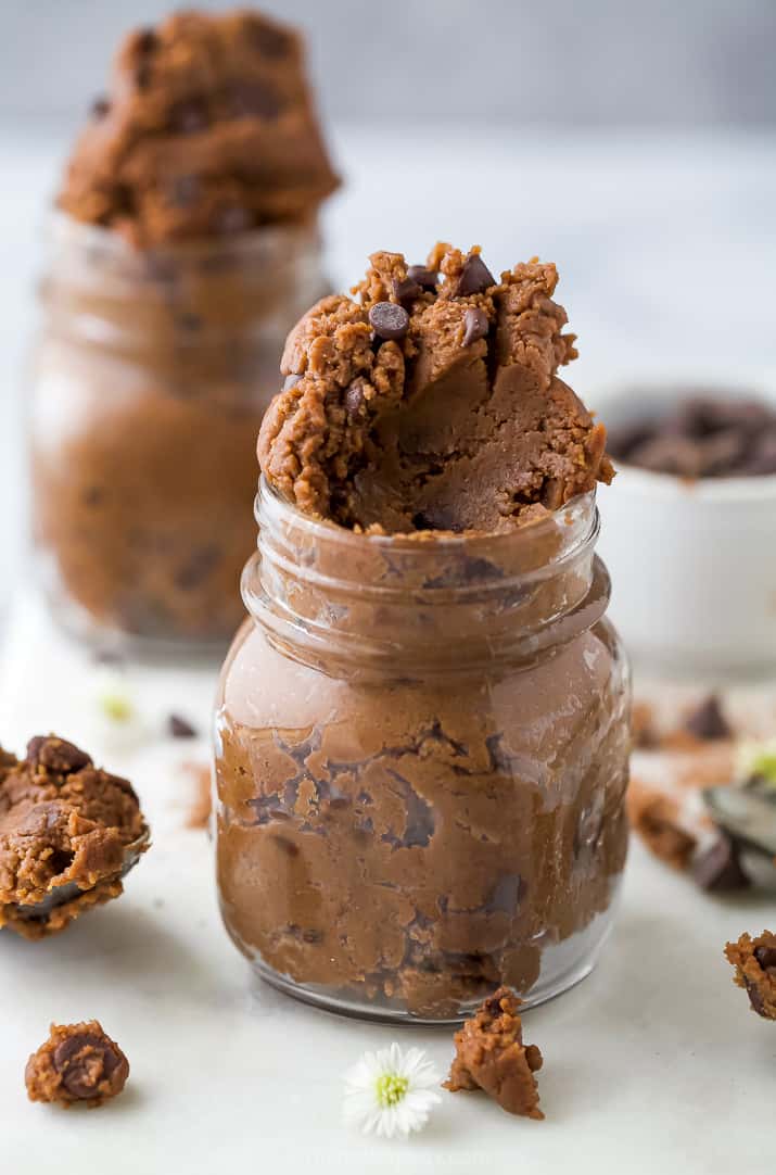 close up of vegan edible brownie batter in a jar with a scoop taken out of it