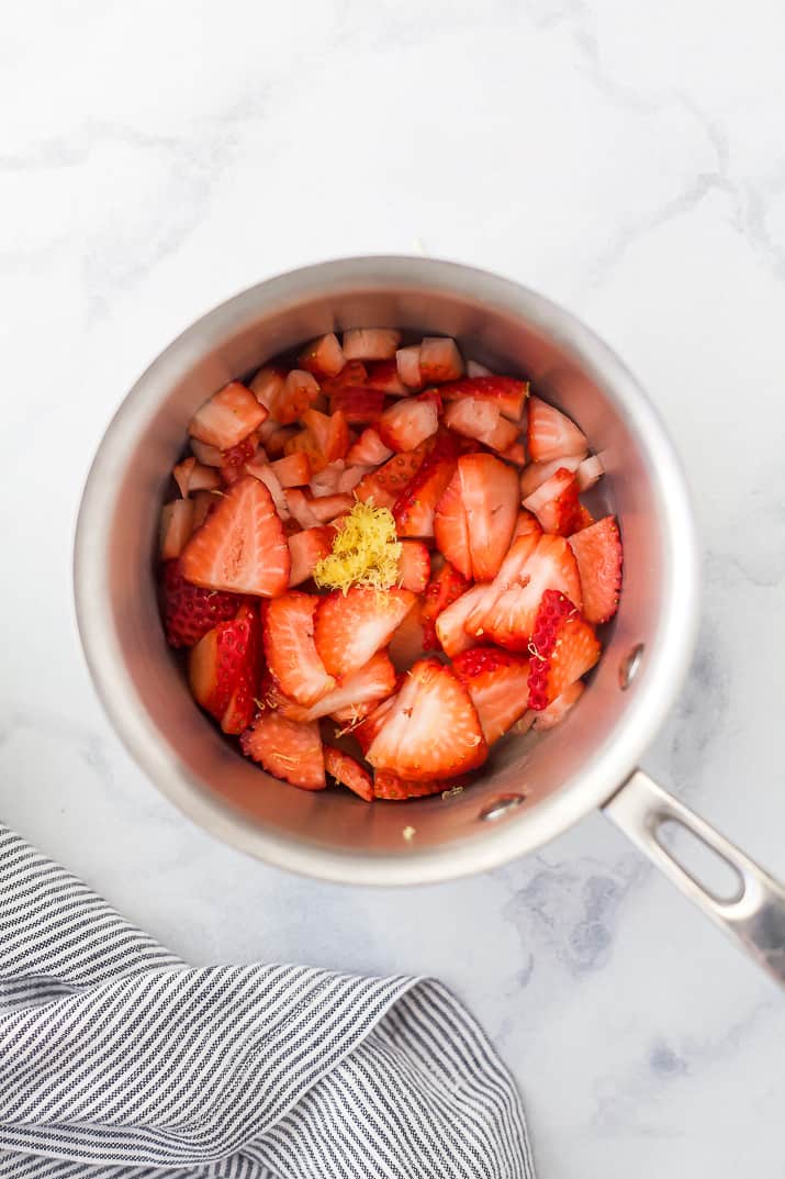 Ingredients for strawberry compote in saucepan.