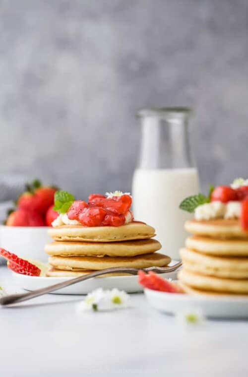 a stack of healthy fluffy pancakes with strawberry compote on top