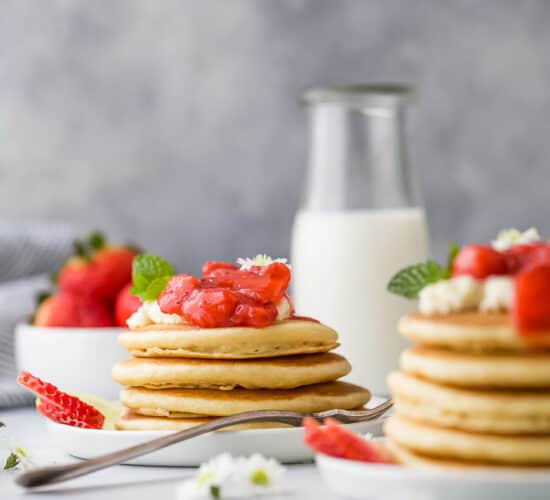 a stack of healthy fluffy pancakes with strawberry compote on top