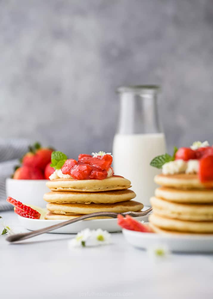 a stack of healthy fluffy pancakes with strawberry compote on top