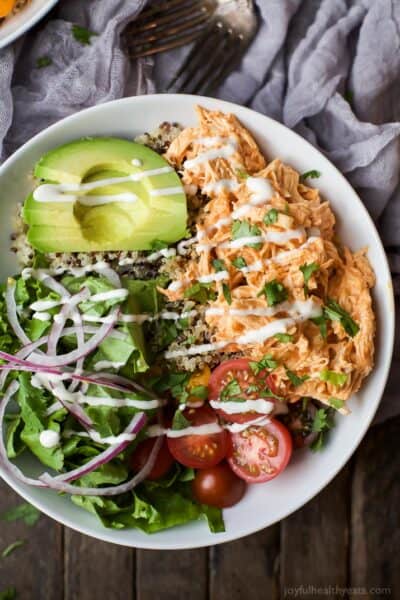 overhead photo of buffalo chicken quinoa bowls with a drizzle of ranch dressing