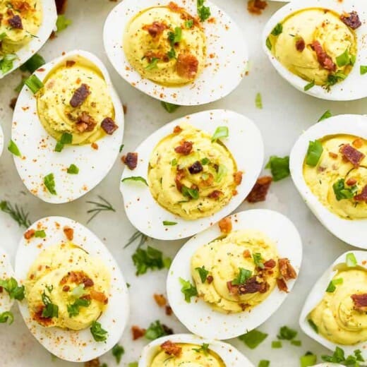 close up photo of classic deviled eggs recipe topped with bacon and chives