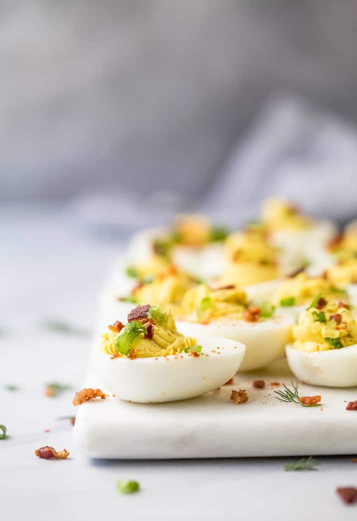 a side photo of classic deviled egg with bacon topped with chives