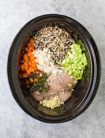 a crock pot full of ingredients for chicken and wild rice soup