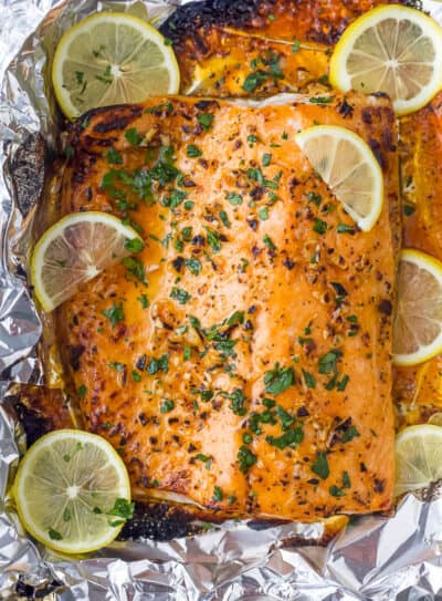 overhead photo of garlic butter baked salmon in foil with lemons on top