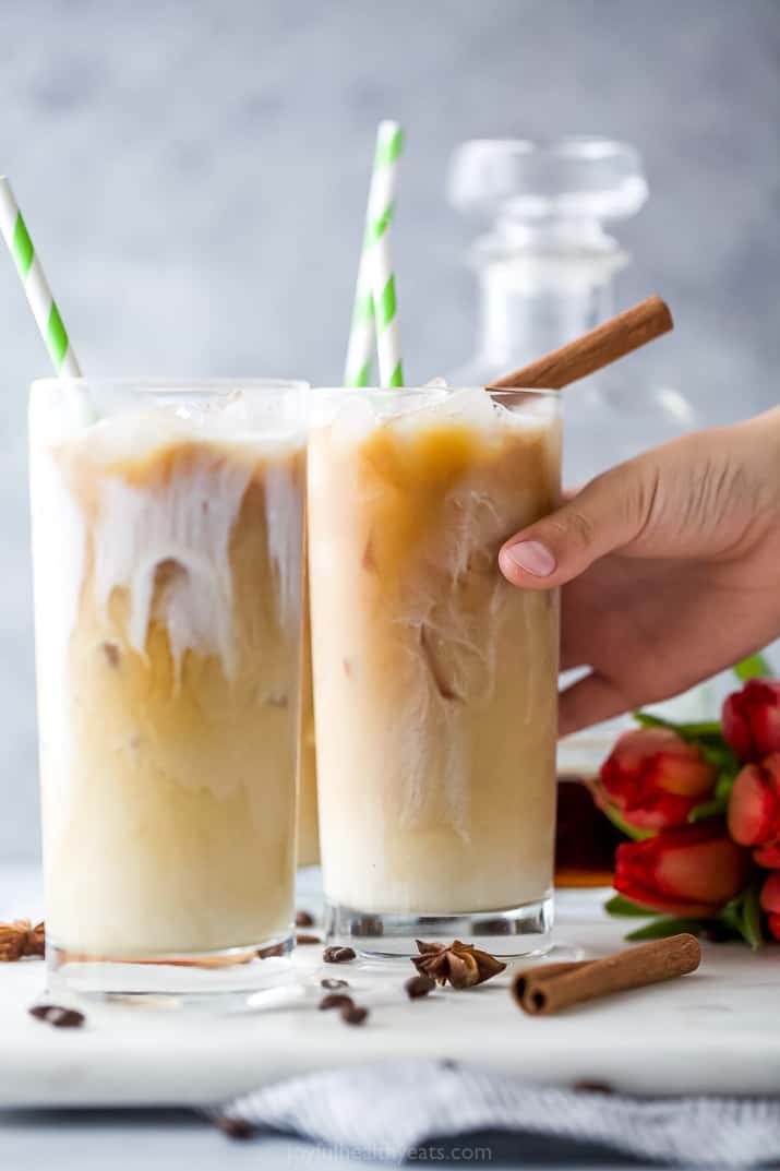 a hand grabbing a cup filled with iced chai tea latte