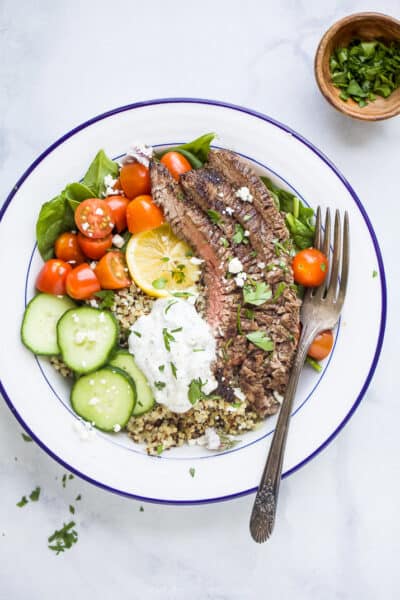 overhead photo of easy mediterranean steak and quinoa bowls with tzatziki sauce