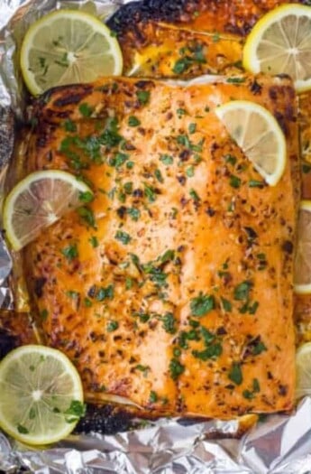 overhead photo of garlic butter baked salmon in foil with lemons on top