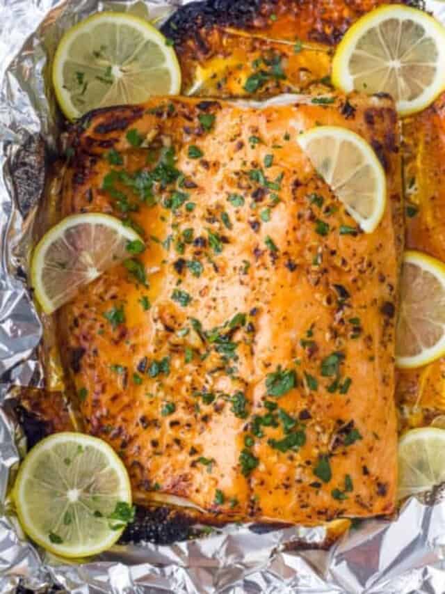 overhead p،to of garlic ،er baked salmon in foil with lemons on top