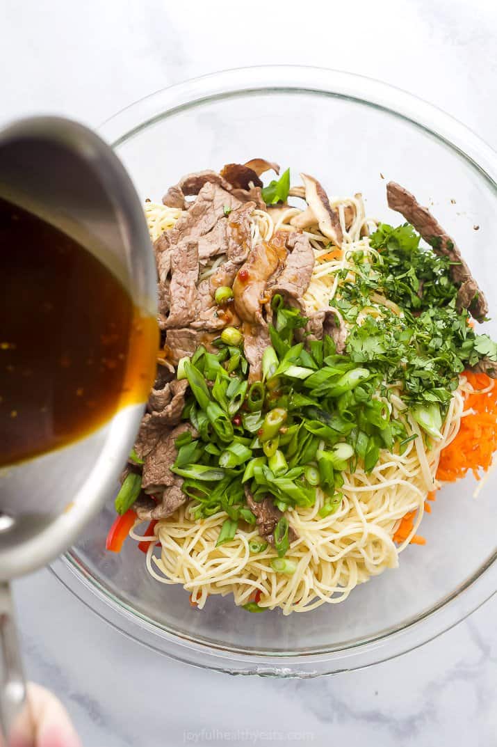 pouring kung pao sauce over beef noodles and vegetables