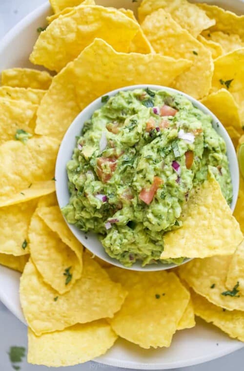 the best guacamole recipe in a bowl with tortilla chips around it