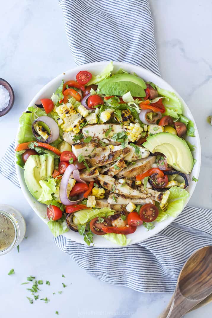 a bowl filled with grilled honey mustard chicken salad with avocado