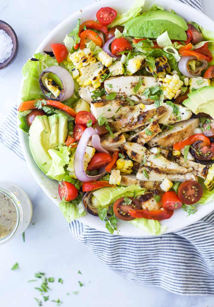 a bowl filled with grilled honey mustard chicken salad topped with veggies and avocado