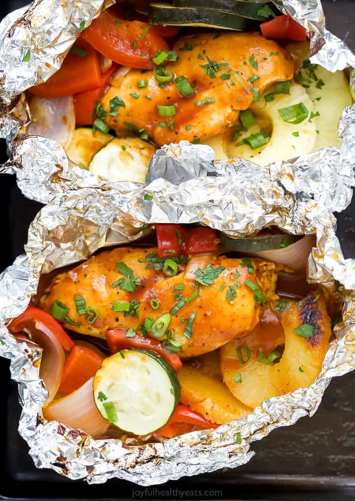 two foil packets filled with grilled hawaiian bbq chicken and vegetables