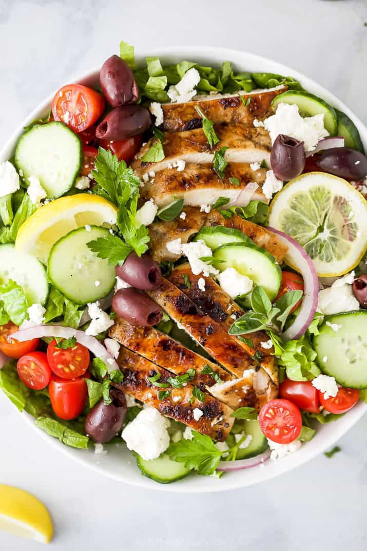 light greek salad with grilled chicken in a bowl topped with greek dressing
