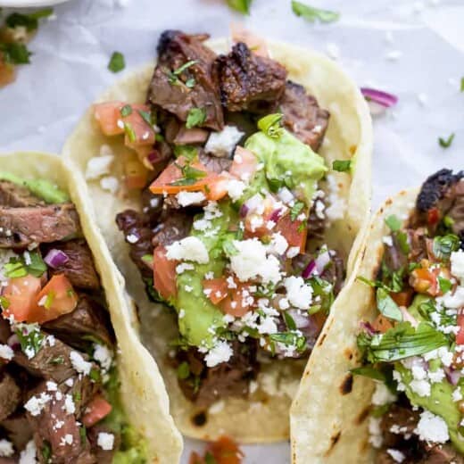 corn tortillas filled with marinated carne asada meat and avocado crema
