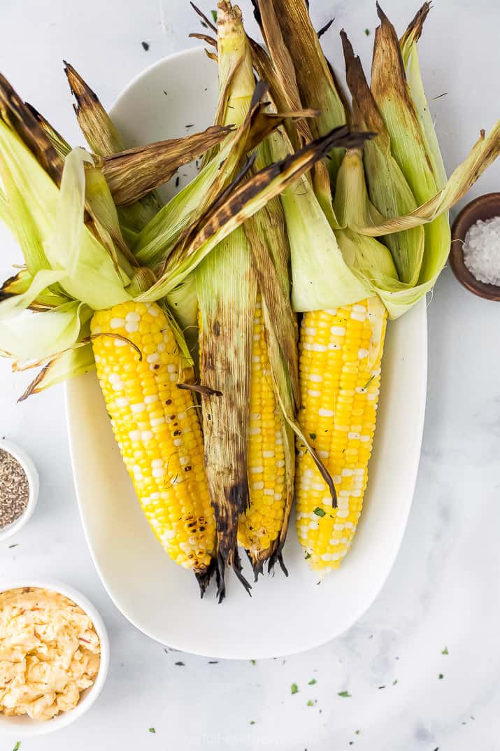 grilled corn on the cob topped with honey chipotle butter on a plate