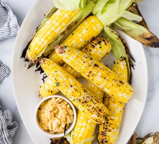 a plate filled with grilled corn on the cob and honey chipotle butter
