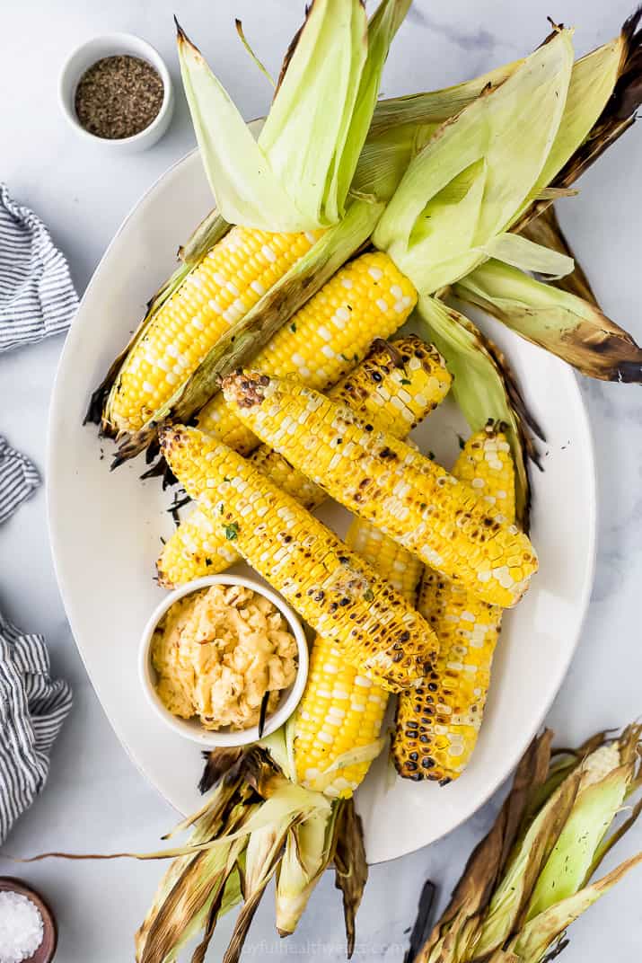 a plate filled with grilled corn on the cob and honey chipotle butter