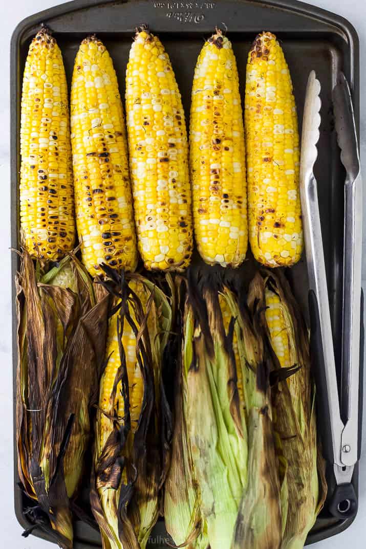 a baking sheet filled with grilled corn on the cob