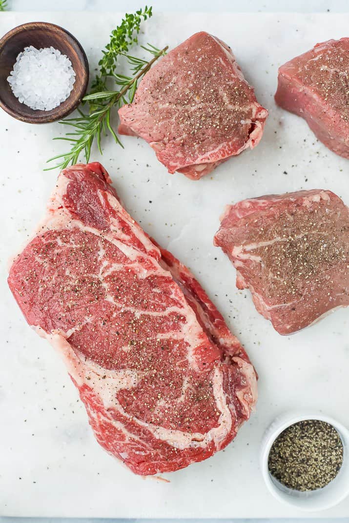 raw steaks seasoned with salt and pepper