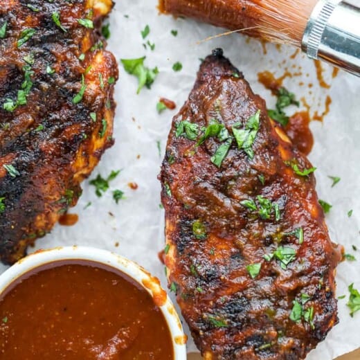 overhead photo of best ever bbq chicken on a sheet pan with bbq sauce covered brush