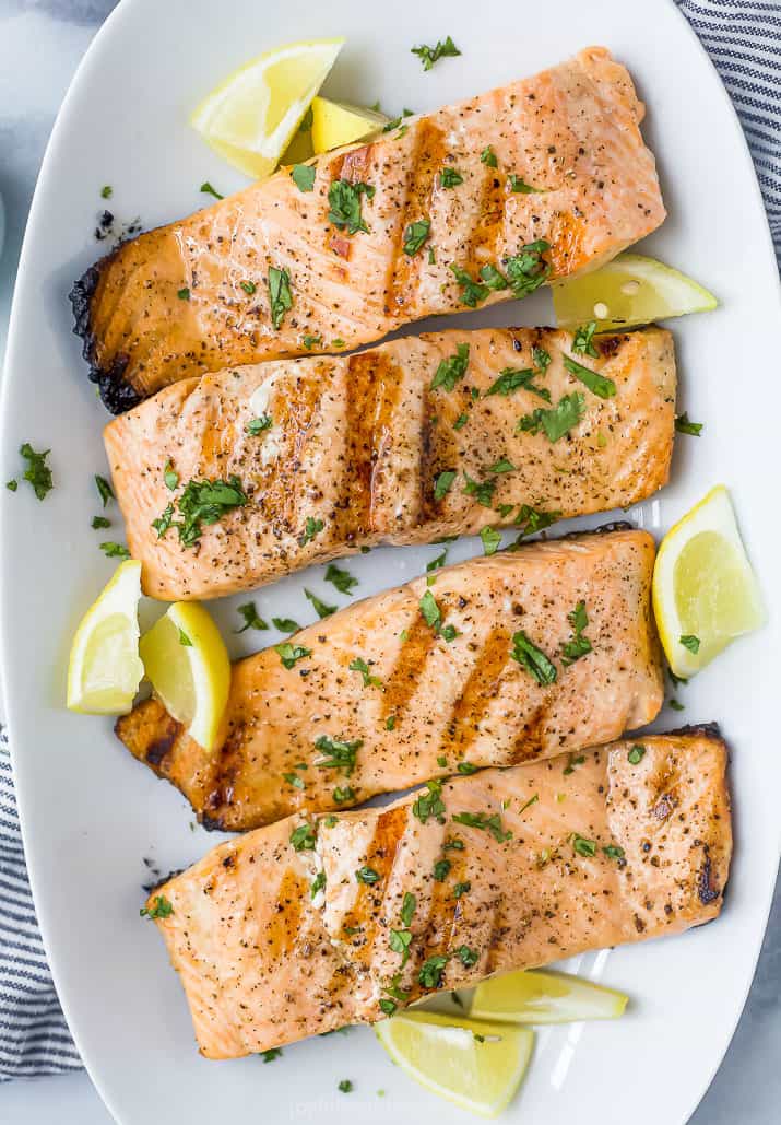 closeup photo of grilled salmon topped with lemon and fresh herbs