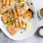 grilled salmon on a plate topped with lemon and fresh herbs