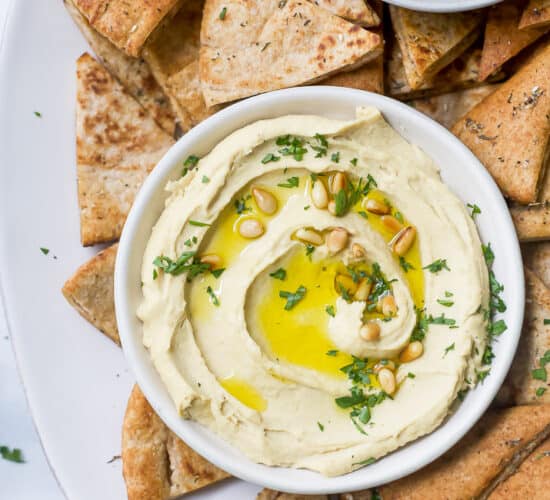 overhead view of a bowl filled with homemade classic hummus served with baked pita chips