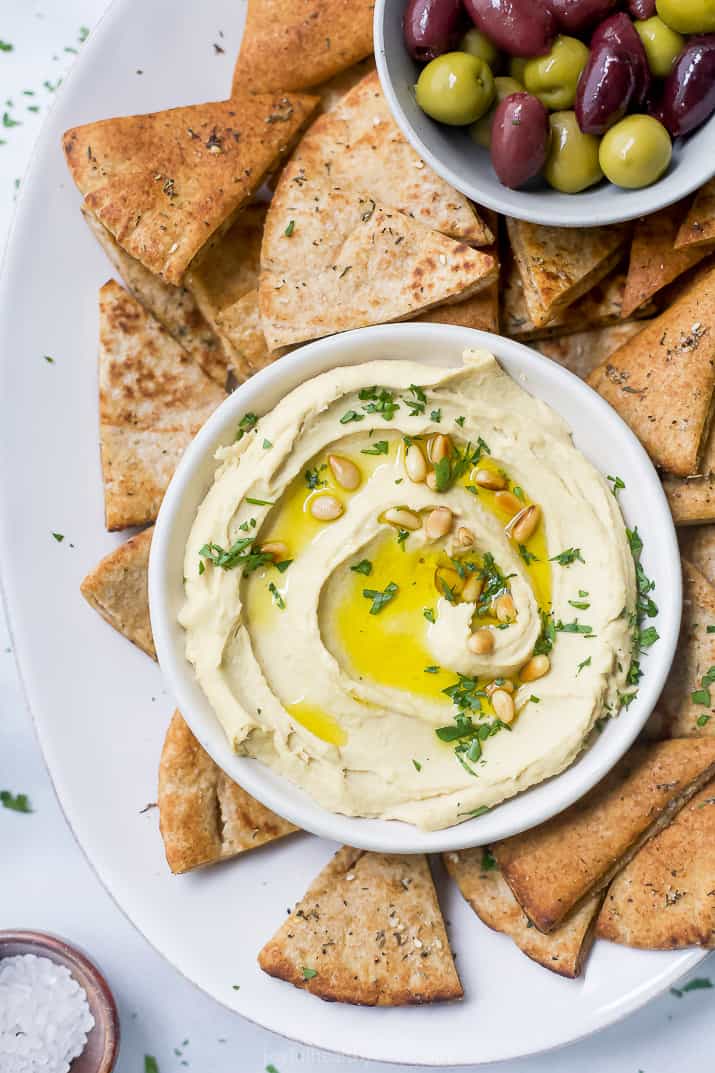 overhead view of a bowl filled with homemade classic hummus served with baked pita chips