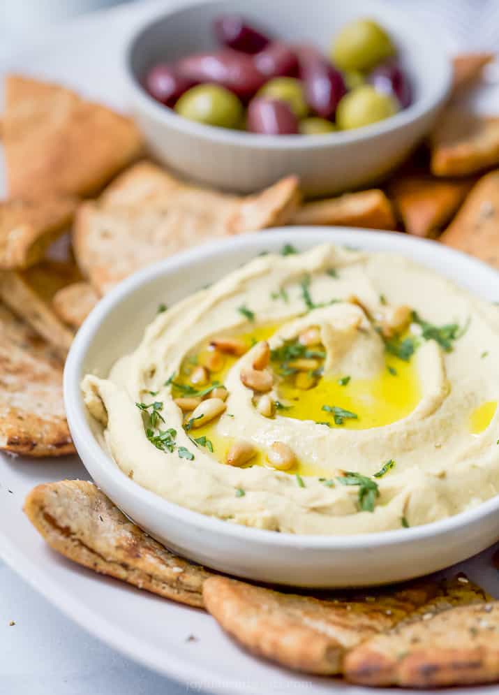 A bowl filled with creamy homemade hummus with baked pita chips