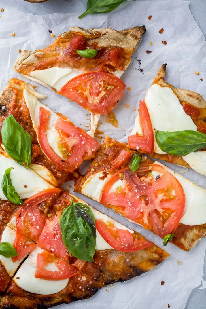 cut up pieces of the best grilled pizza recipe with margherita toppings